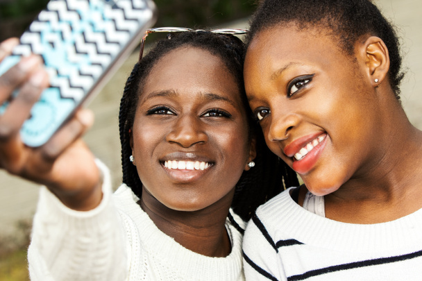 スマート フォンで selfie を取っているアフリカの女の子. - 写真・画像