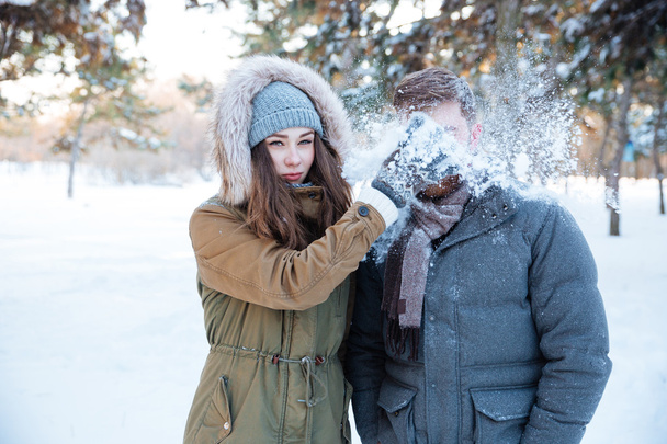 Amusing woman thowing snowball in her boyfriend face  - Photo, Image