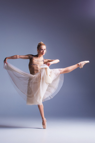 Young beautiful ballerina dancer dancing on a studio background - Valokuva, kuva