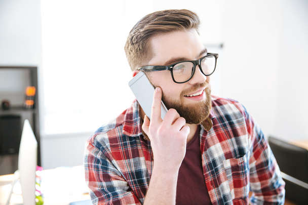 Happy man with beard in glasses talking on cell phone - 写真・画像