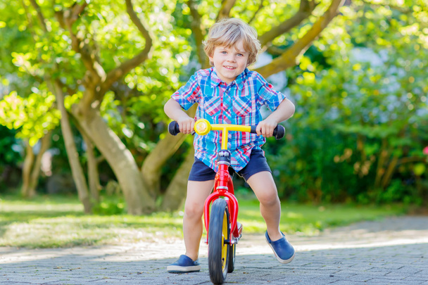 niño niño conduciendo triciclo o bicicleta en el jardín
 - Foto, imagen