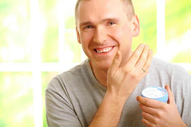 Hombre aplicando crema facial
 - Foto, Imagen