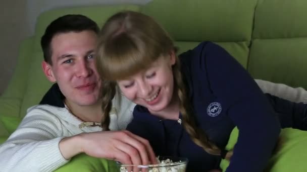 Young couple with popcorn watching comedy on television and laugh. - 映像、動画