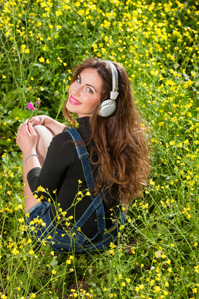 Krásná mladá dívka s sluchátka v květiny - Fotografie, Obrázek