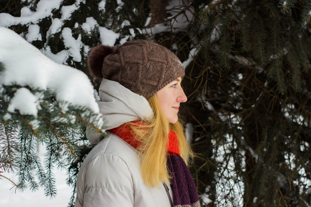 Young beautiful woman stand behind the trees in winter season - Foto, imagen