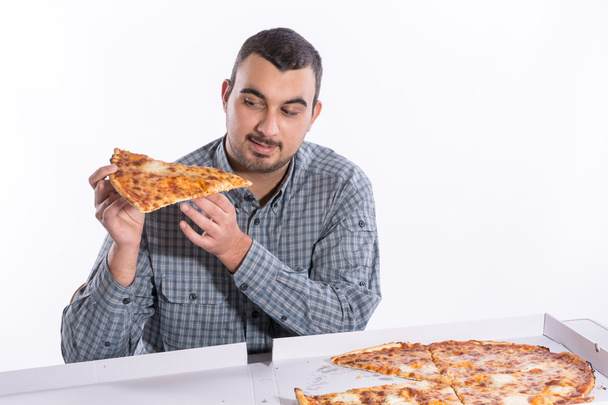 Young man eating pizza with cheese on a white background - Foto, afbeelding