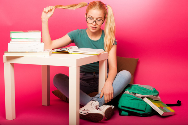 Playful schoolgirl with big eyeglasses concentrated in reading b - Φωτογραφία, εικόνα