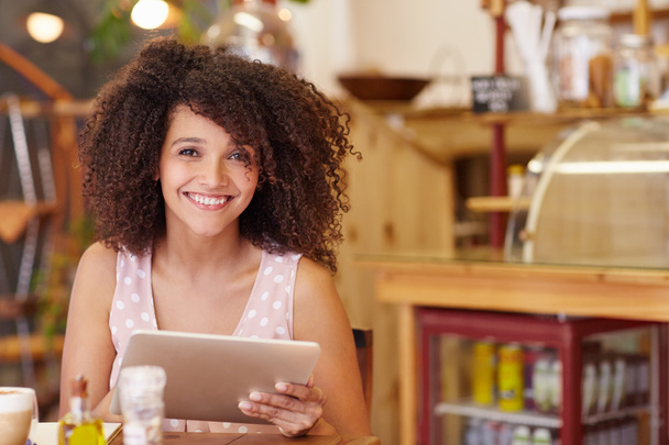woman smiling and holding tablet in cafe - Foto, Bild