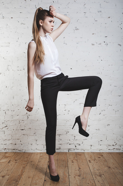 fashion model in black trousers and white top posing over white background - Foto, immagini