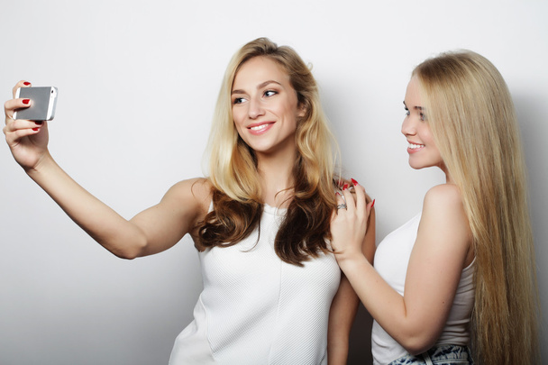 two young women taking selfie with mobile phone - Fotoğraf, Görsel