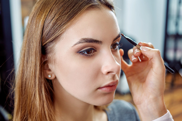 young, beautiful girl apply makeup on a eyebrows in a beauty salon - Photo, Image