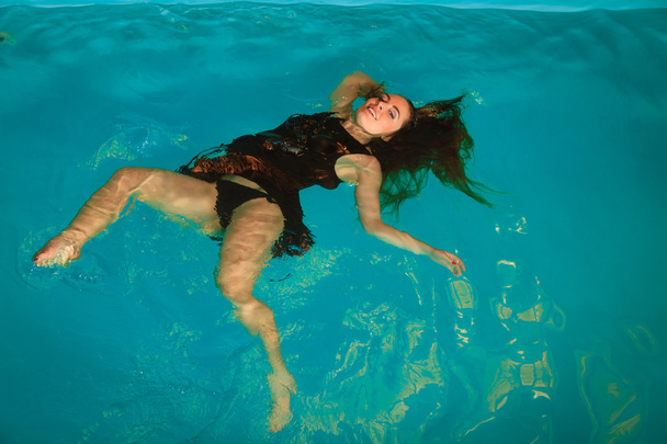 Woman floating  in swimming pool - Foto, afbeelding