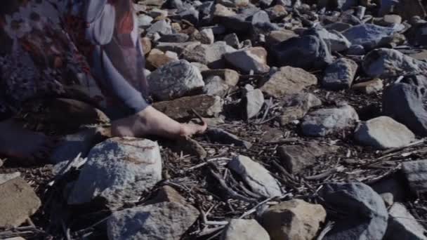 El detalle de cerca de los pies femeninos en el vestido largo que se encuentra sobre las piedras grandes con la tierra
 - Metraje, vídeo
