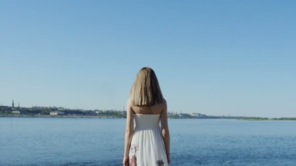 Девушка в белом платье смотрит на город через реку задний вид
 - Кадры, видео