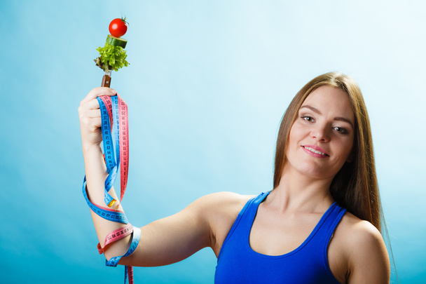 Fit girl with vegetarian food and measuring tape. - Photo, Image