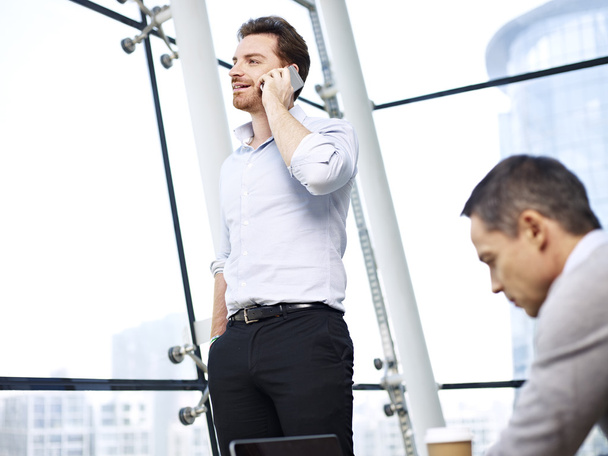 деловой человек разговаривает по мобильному телефону в офисе
 - Фото, изображение