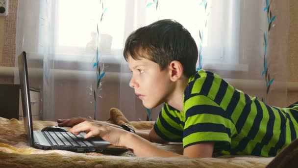 boy laptop internet browsing is playing lying in bed - Footage, Video