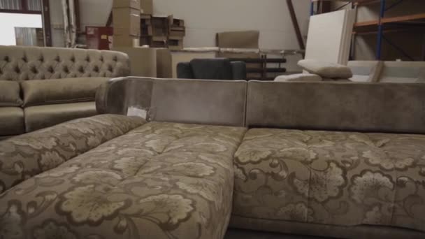 Frau in Arbeitsuniform hebt in Möbelfabrik ein Sofa auf - Filmmaterial, Video