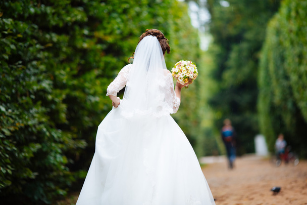 Gorgeous stylish blonde bride in vintage white dress walking in the park - Foto, Imagen