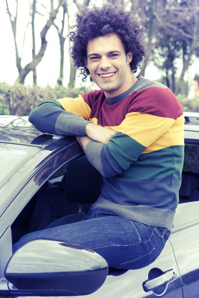 Cool man smiling looking camera sitting on car window vintage look - Foto, immagini