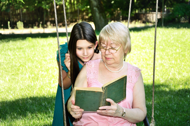 dziewczyna i jej babcia poczytać książkę w parku poziome - Zdjęcie, obraz