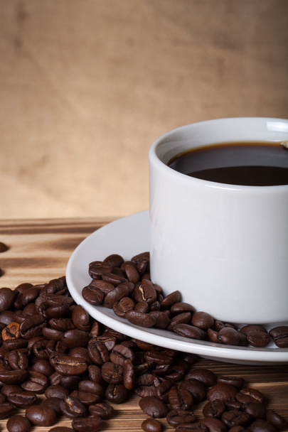 Granos de café y café en taza blanca en la mesa de madera frente a un
  - Foto, imagen