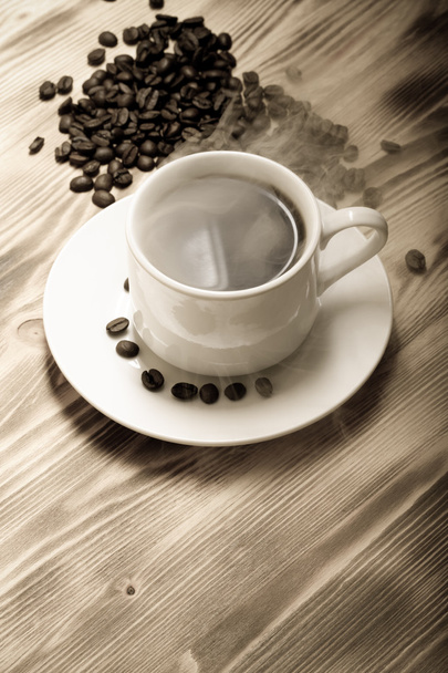 Coffee beans and coffee in white cup on wooden table. Selective  - Photo, Image