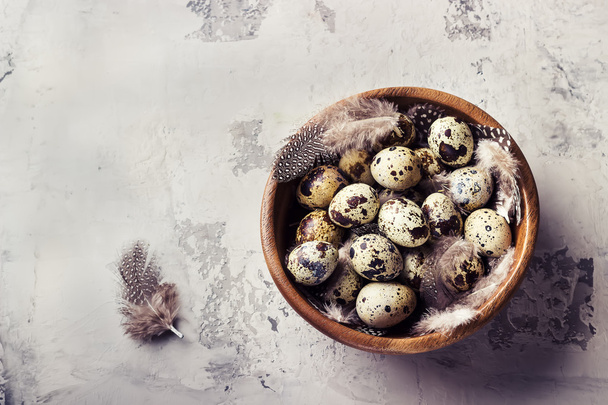 Quail eggs in a wooden bowl on a concrete background. - Zdjęcie, obraz