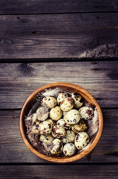Quail eggs in a wooden bowl on a gray wooden background.  - Φωτογραφία, εικόνα