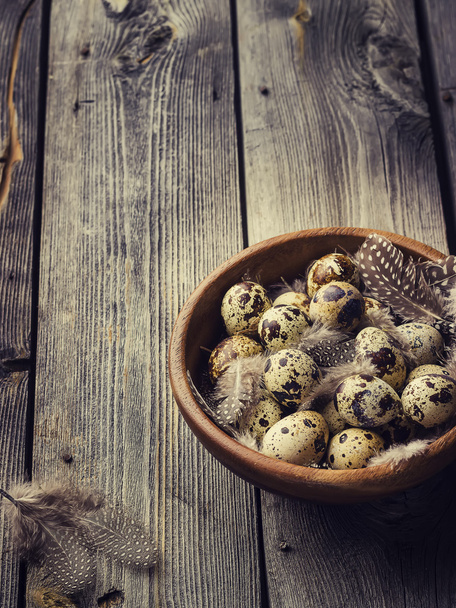 Quail eggs in a wooden bowl on a gray wooden background.  - Φωτογραφία, εικόνα