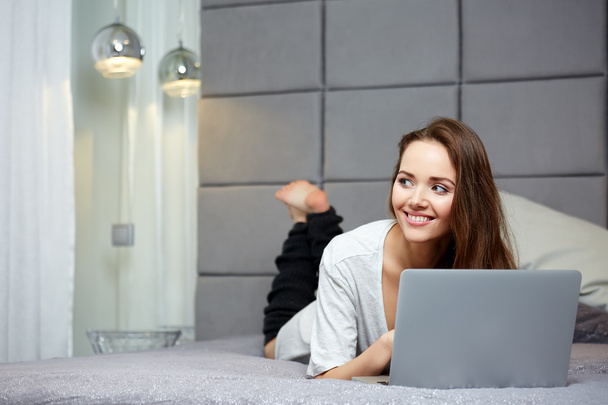 Pretty woman using laptop at home in bedroom - Zdjęcie, obraz
