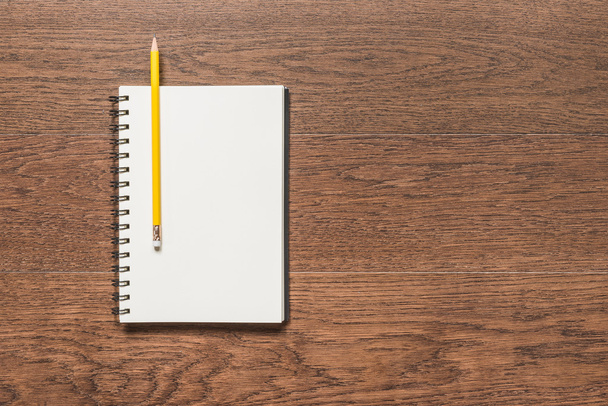 gele potlood met lege nota boek op houten achtergrond - Foto, afbeelding