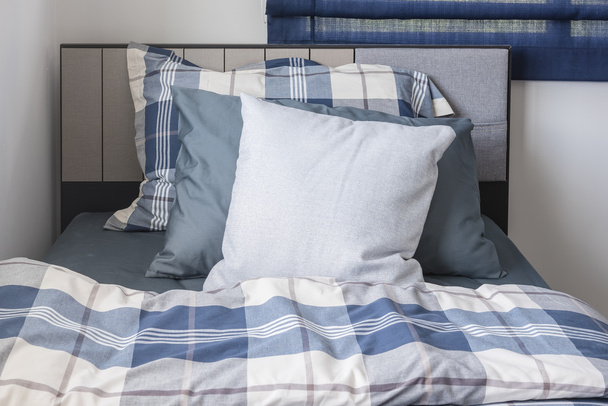 kussens op moderne bed met blauwe kleurtoon  - Foto, afbeelding