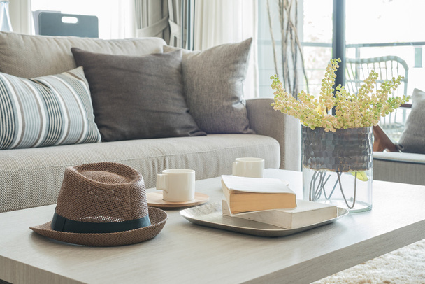 šedá pohovka a polštáře s kloboukem na dřevěný stůl  - Fotografie, Obrázek