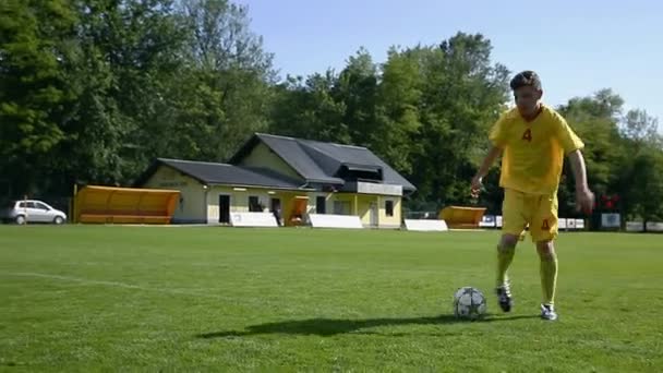 nastolatek gry w piłkę nożną na zielony trawnik - Materiał filmowy, wideo