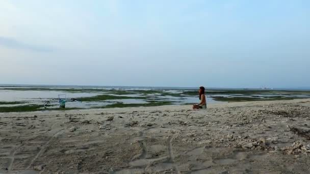Mujer meditando en la playa al atardecer
 - Metraje, vídeo