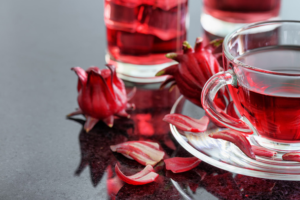 Closeup view of cup of hibiscus tea (rosella, karkade) on table - Фото, зображення