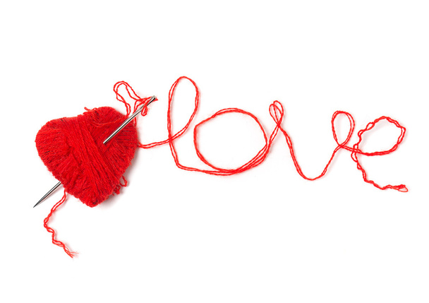 Heart of red threads pierced by a needle. Isolated on a white background - Foto, afbeelding