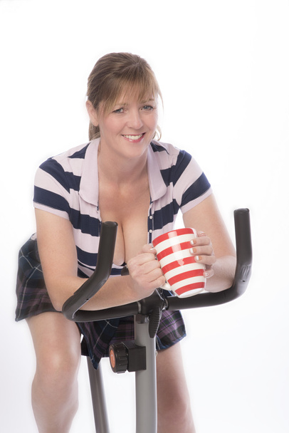 Женщина на велотренажере с кружкой чая
 - Фото, изображение