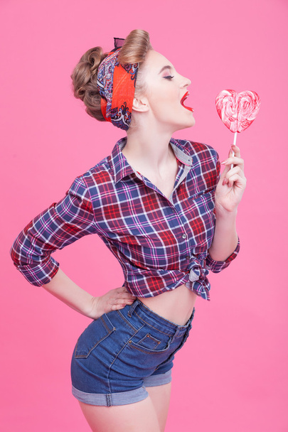 Cute pin-up girl is tasting sweet lollipop - Foto, imagen