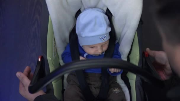 Vater setzt Baby in einen speziellen Sitz - Filmmaterial, Video