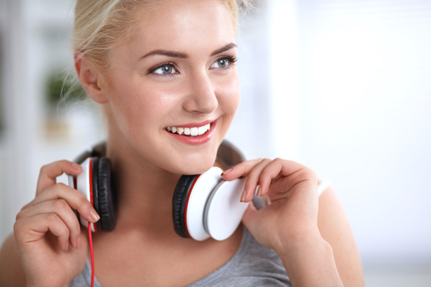Young beautiful woman at home sitting on sofa and listening music - Photo, image