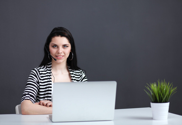 Beautiful business woman working at her desk with headset and laptop - Foto, afbeelding