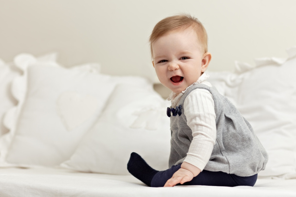 Little girl sitting on bed and laughing - Фото, зображення