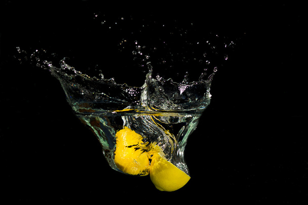 Lemon in water on black background - 写真・画像