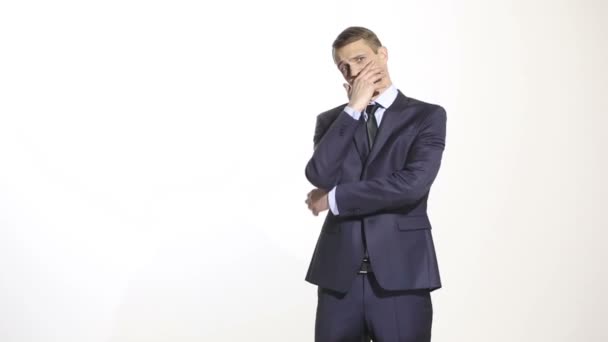 gestures distrust lies. body language. man in business suit isolated on white background. closed position. closes mouth by hand. his arms - Footage, Video