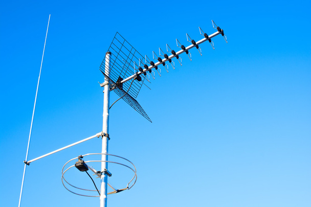 einfacher Antennenmast mit Antennen zum Empfang digitaler Fernseh- und Radiosignale, dvb-t, dvb-t2 und fm (horizontale Polarisation) einschließlich verzögertem Blitzableiter. Der Hintergrund ist blauer Himmel. - Foto, Bild