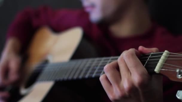 Um músico talentoso tocando guitarra acústica no escuro. O tipo a cantar e a tocar. Close-up
. - Filmagem, Vídeo