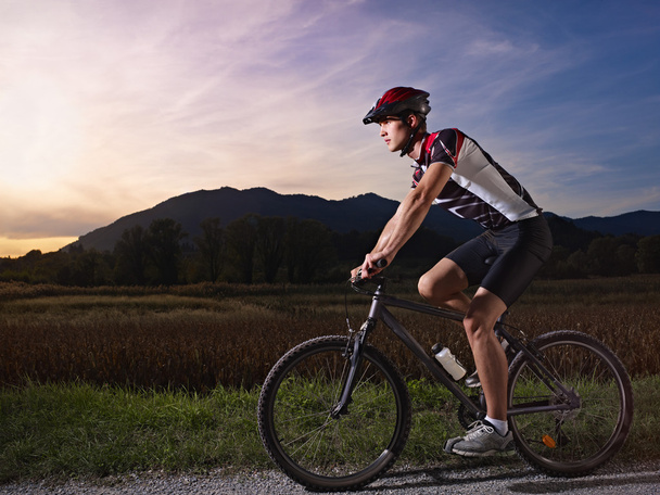 młody człowiek treningu na rowerze górskim na zachodzie słońca - Zdjęcie, obraz