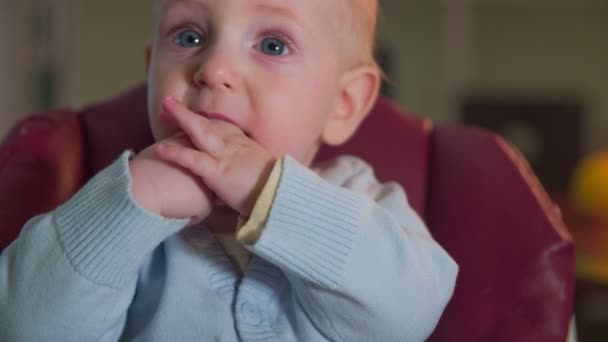 Χαριτωμένο παιδί κάθεται στην κόκκινη καρέκλα - Πλάνα, βίντεο